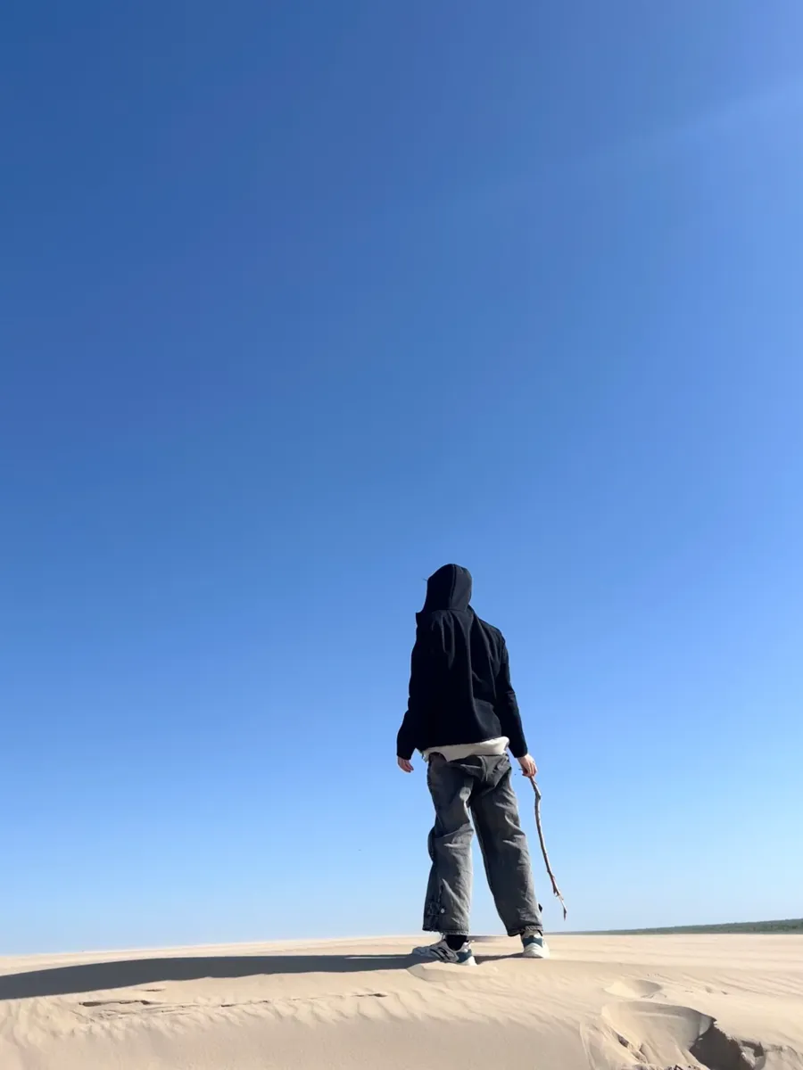 Standing alone on top of a sand dune under blue sky