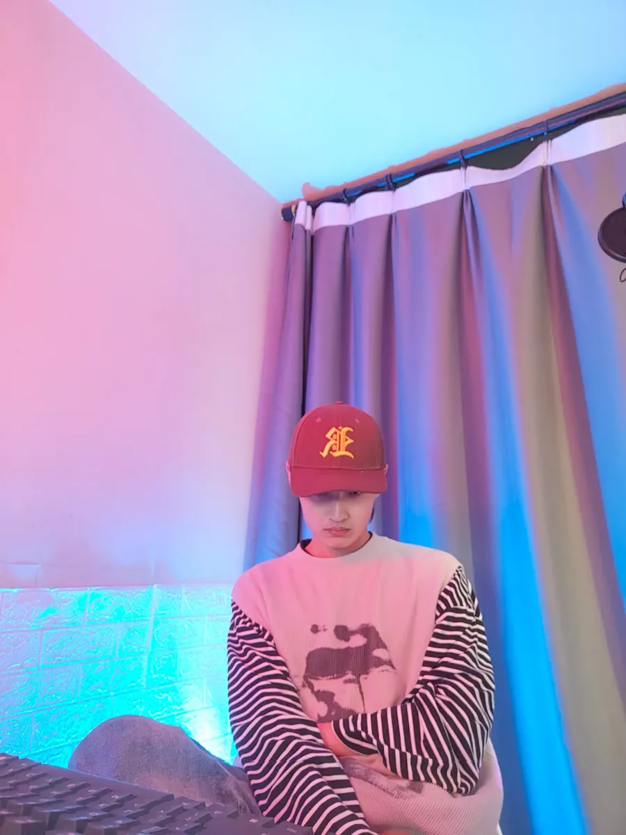 Sitting in a red cap in a pink and blue lit room