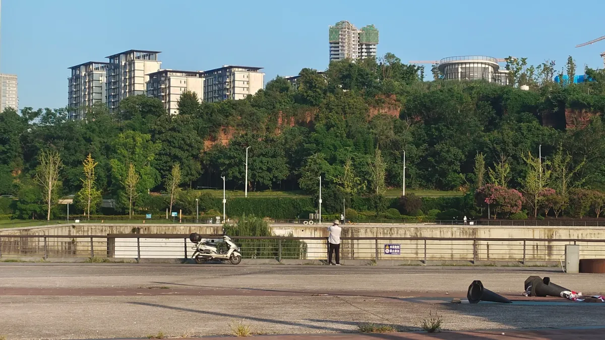 Riverside promenade with green hills on a sunny day